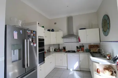 a kitchen with white cabinets and a stainless steel refrigerator at Villa Cottage Reine, RC Jardin in Cannes