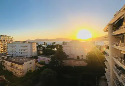 a sunset over a city with buildings and the ocean at Amazing sea view, parking, easy beach access in Cannes