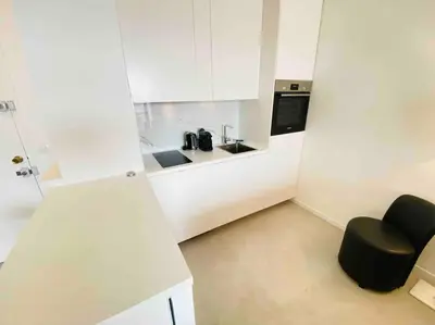 a small white kitchen with a black chair in it at Amazing sea view, parking, easy beach access in Cannes