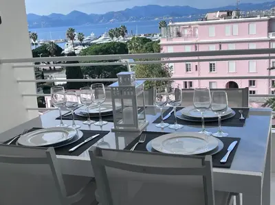 a table with wine glasses and plates on a balcony at Amazing sea view, parking, easy beach access in Cannes