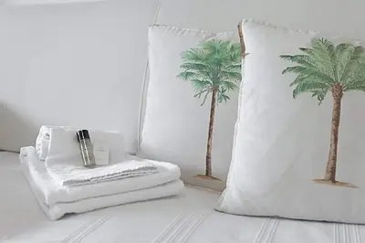 a white pillow with a cigarette and palm trees on it at LE BELLA studio avec balcon idéal pour une évasion à deux, au calme et proche du centre-ville in Cannes