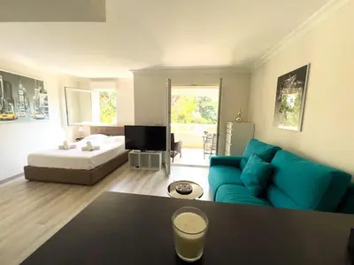 a living room with a blue couch and a bed at Charmant Studio avec terrasse et vue arborée in Cannes