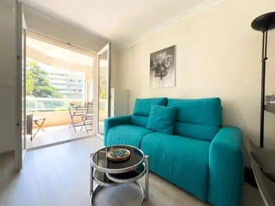 a living room with a blue couch and a table at Charmant Studio avec terrasse et vue arborée in Cannes