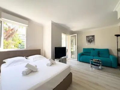 a bedroom with a white bed and a blue couch at Charmant Studio avec terrasse et vue arborée in Cannes