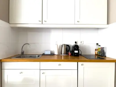 a kitchen counter with a sink and white cabinets at Charmant Studio avec terrasse et vue arborée in Cannes