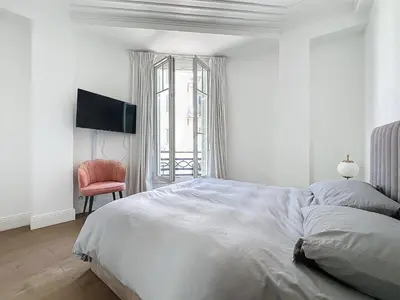 a white bedroom with a bed and a red chair at INTUITION - 2 pieces - Cannes Carre d or in Cannes