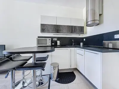 a kitchen with white cabinets and a black counter top at Intuition 2 lits 2'' Croisette et Palais des Festivals in Cannes