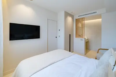 a white bedroom with a bed and a tv on the wall at Beautiful 3 bedroom fully renovated in Cannes