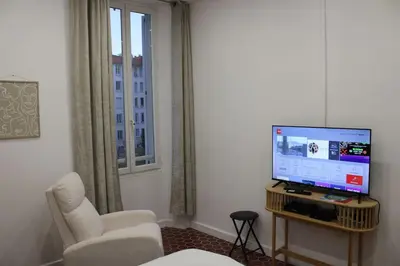 a living room with a tv and a chair and a window at Cocon Spacieux équipé Quartier Prado in Cannes