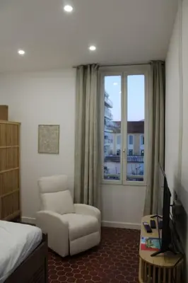 a bedroom with a bed and a chair and a window at Cocon Spacieux équipé Quartier Prado in Cannes