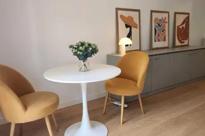 a white table with two chairs and a vase of flowers at Studio calme avec vue sur un grand Pin parasol in Cannes
