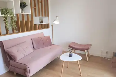a living room with a pink couch and a table at Studio calme avec vue sur un grand Pin parasol in Cannes