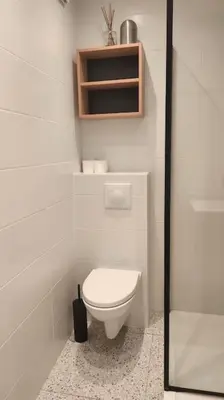 a white bathroom with a toilet and a shelf at Studio calme avec vue sur un grand Pin parasol in Cannes