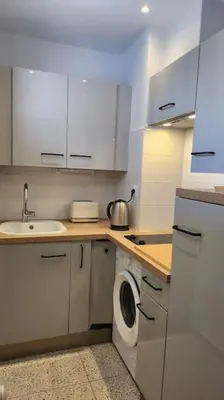 a white kitchen with a washing machine and a sink at Studio calme avec vue sur un grand Pin parasol in Cannes