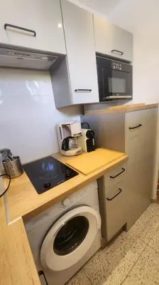 a small kitchen with a washing machine and a microwave at Studio calme avec vue sur un grand Pin parasol in Cannes