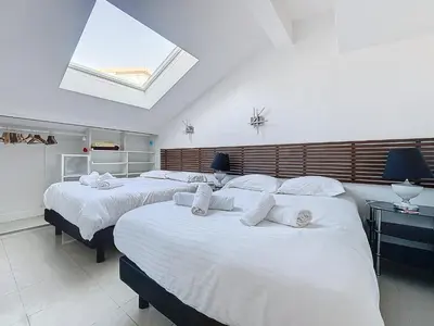 a bedroom with two beds with white sheets and a skylight at INTUITION - Cannes centre - 6-8 Couchages in Cannes