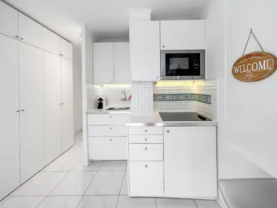 a white kitchen with white cabinets and a microwave at Studio lumineux, WIFI à deux pas de la Croisette in Cannes