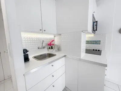 a white kitchen with white cabinets and a sink at Studio lumineux, WIFI à deux pas de la Croisette in Cannes