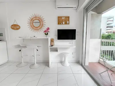 a white kitchen with a sink and a tv on a wall at Studio lumineux, WIFI à deux pas de la Croisette in Cannes