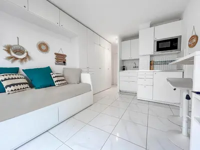 a white kitchen with white cabinets and a couch at Studio lumineux, WIFI à deux pas de la Croisette in Cannes