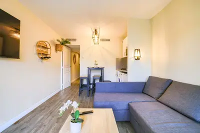 a living room with a blue couch and a table at Le Cannes Beach 408 - cosy Balcon Piscine Netflix in Cannes