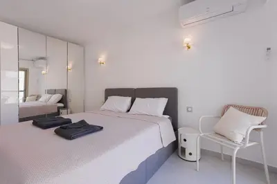 a white bedroom with two beds and a chair at 7 Pradignac Full 3bdrs by Halldis in Cannes