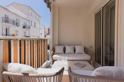 a balcony with a bed and chairs and a table at 7 Pradignac Full 3bdrs by Halldis in Cannes