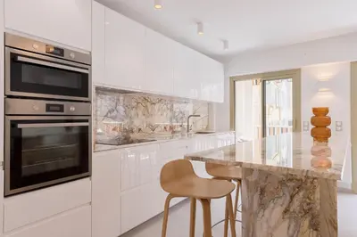 a white kitchen with a marble counter and a chair at 7 Pradignac Full 3bdrs by Halldis in Cannes