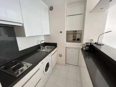 a kitchen with white cabinets and a sink and a dishwasher at 204 - Cannes La Croisette - Studio face mer avec balcon in Cannes