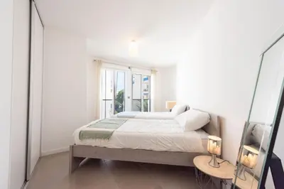 a white bedroom with a bed and a window at 3-Br Apartment with Pool Parking & Beaches 100m away in Cannes