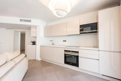 a white kitchen with white cabinets and a couch at 3-Br Apartment with Pool Parking & Beaches 100m away in Cannes