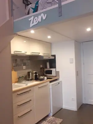 a kitchen with white cabinets and a stove top oven at le cosy de carole in Cannes