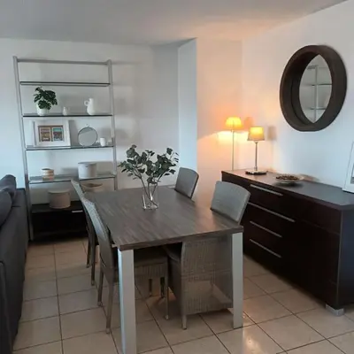 a dining room with a table with chairs and a mirror at Apt calme 2 chambres vue dégagée in Cannes