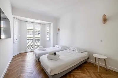 two beds in a white room with a window at Elegance and Refinement, proximity to La Croisette in Cannes