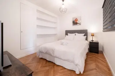 a bedroom with a large white bed and wooden floors at Triplex Gallia Luxe Cannes in Cannes