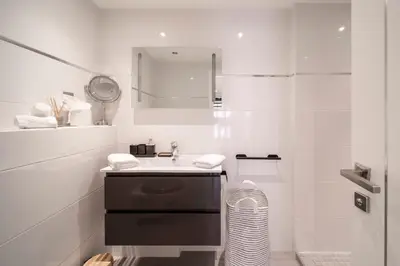 a white bathroom with a sink and a mirror at Triplex Gallia Luxe Cannes in Cannes