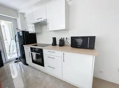 a kitchen with white cabinets and a black microwave at INTUITION - 3 pieces - 10min Croisette in Cannes
