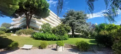 a building with a tree and a bench in a park at Les Orangers - Cannes - Sea View- Swimming Pool - Free Parking - Beach in Cannes