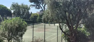 a tennis court with a net and some trees at Les Orangers - Cannes - Sea View- Swimming Pool - Free Parking - Beach in Cannes