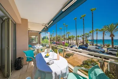 a balcony with tables and chairs and a view of the beach at Croisette vue mer 2 pièces in Cannes