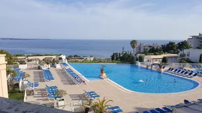 a large swimming pool with blue chairs and the ocean at Le cannois in Cannes