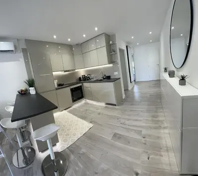 a large white kitchen with a counter and a table at Luxurious 3Bedroom 2 BATH 110 m Apartment Adjoining Hotel Martinez Beachfront in Cannes
