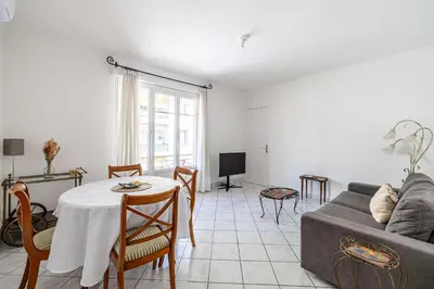a living room with a table and a couch at LE CONNEMARRA avec balcon, lumineux et calme à côté du centre in Cannes