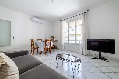 a living room with a couch and a table at LE CONNEMARRA avec balcon, lumineux et calme à côté du centre in Cannes