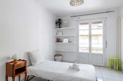 a bedroom with two beds and a window and a door at LE CONNEMARRA avec balcon, lumineux et calme à côté du centre in Cannes