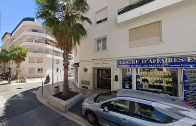 a car parked in front of a building with a palm tree at LE CONNEMARRA avec balcon, lumineux et calme à côté du centre in Cannes