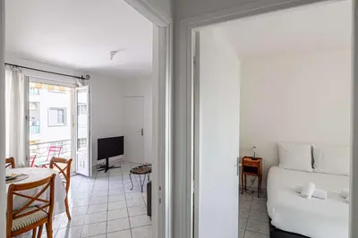 a room with a bed and a table and a television at LE CONNEMARRA avec balcon, lumineux et calme à côté du centre in Cannes