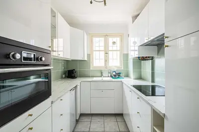 a white kitchen with a sink and a window at LE CONNEMARRA avec balcon, lumineux et calme à côté du centre in Cannes