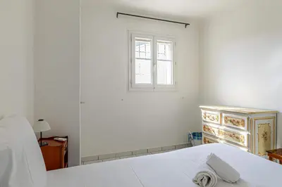 a white bedroom with a bed and a window at LE CONNEMARRA avec balcon, lumineux et calme à côté du centre in Cannes