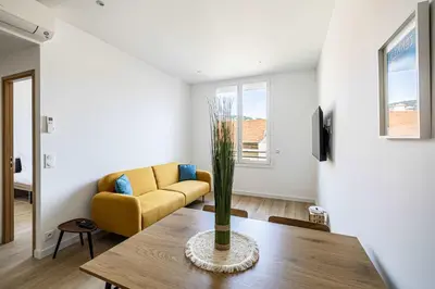 a living room with a table and a yellow couch at LE LOGIS CANNOIS au calme en centre-ville in Cannes